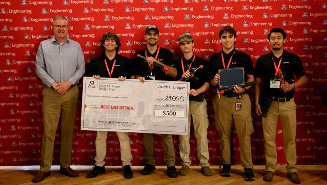 Capstone team 24050 poses with a large check at Design Day 2024.