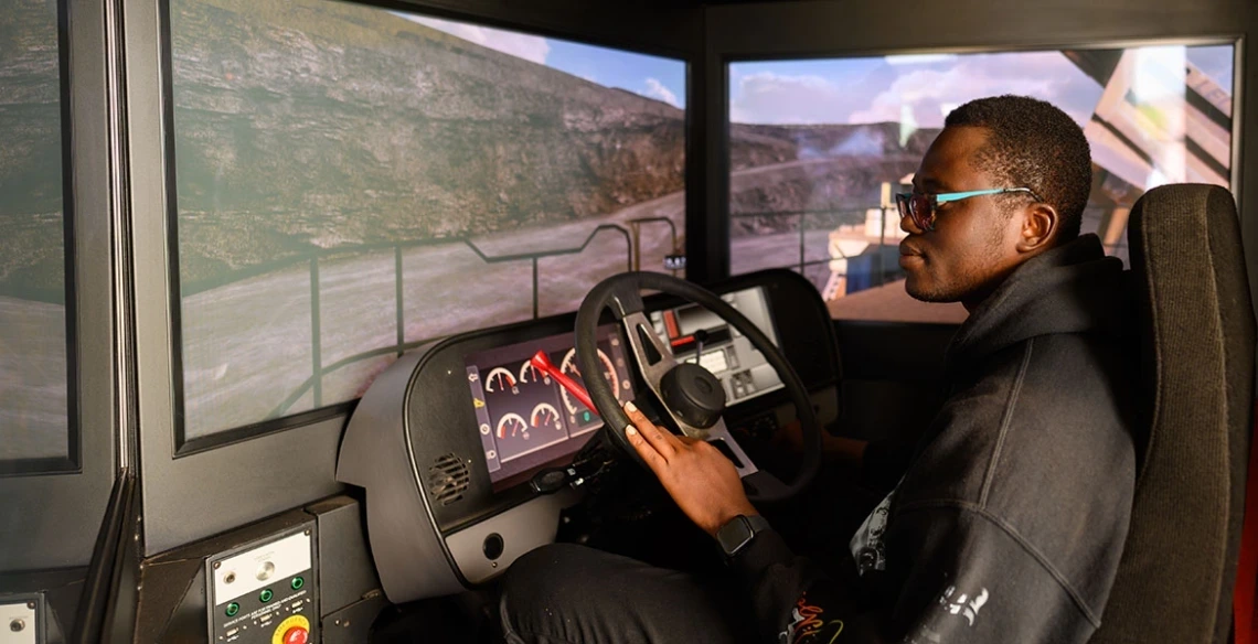 person wearing glasses, behind the wheel of a Freeport-McMoRan’s haul truck simulator